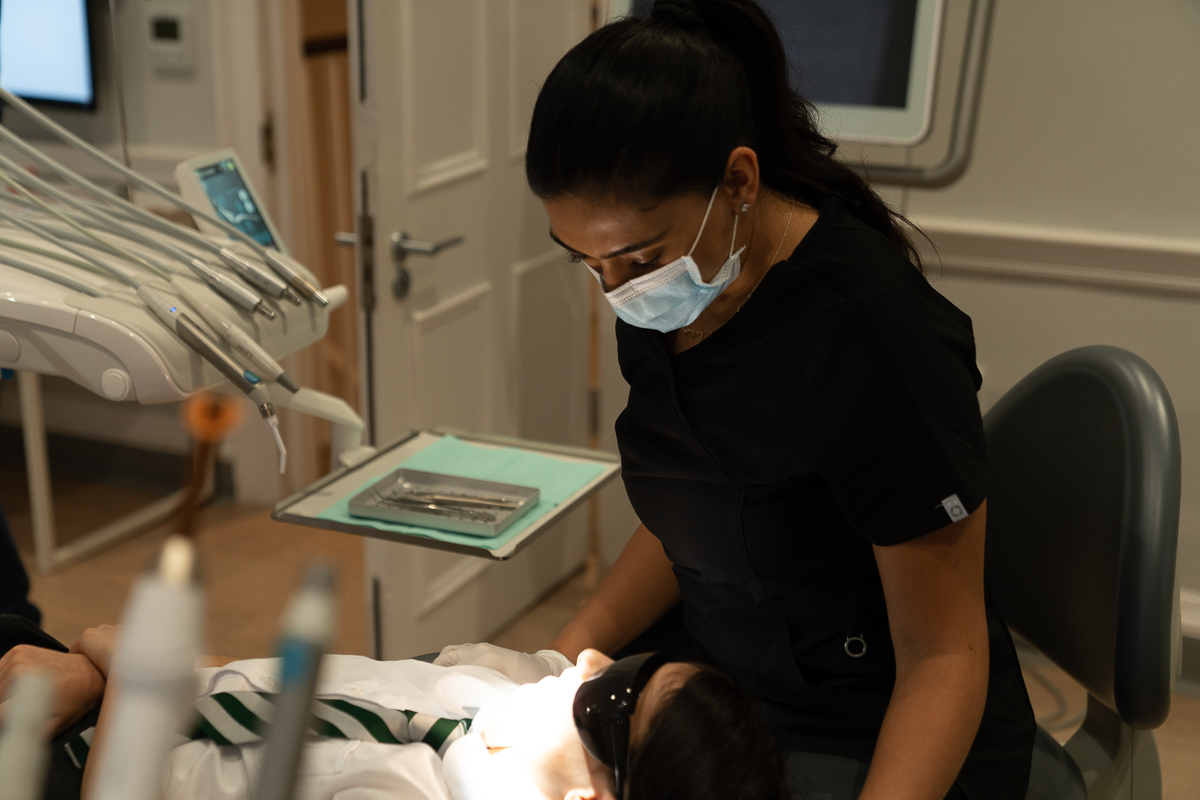 Female dentist sat beside child, smiling and talking. Both look happy and relaxed.